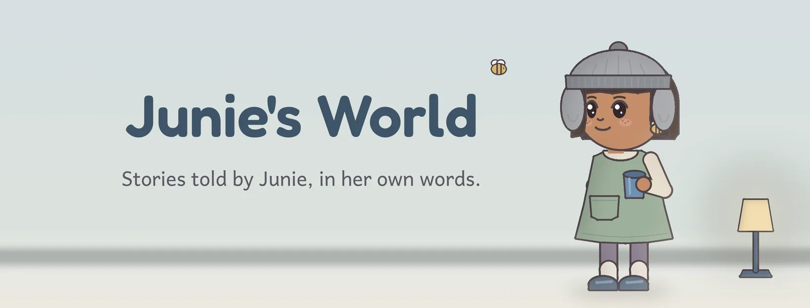 Junie, a girl in a soft gray ear hat and a sage green dress, holds her blue cup next to the words Junie's World.